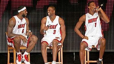 LeBron James, left, and Dwyane Wade listen as new teammate Chris Bosh speaks to fans.