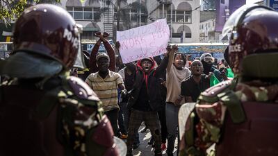 Protesters hold banners and chant anti-government slogans in front of police officers. AFP