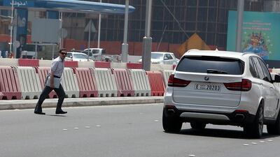 A man crosses Sheikh Zayed Street, through public work barricades. Twenty-six people were counted doing the same in 30 minutes. Pawan Singh / The National