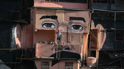 A man works on a giant mural of Venezuelan doctor Jose Gregorio Hernandez in the El Saman de Bolivar community, Caracas. AFP