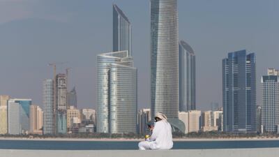 14. SKYLINE: A man relaxes with a coffee and his smartphone in front of the Abu Dhabi skyline. Christopher Pike / The National
