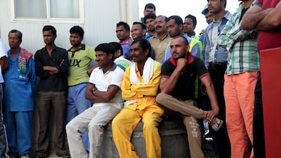 Workers gather to watch a colleague being interviewed. Christopher Pike / The National