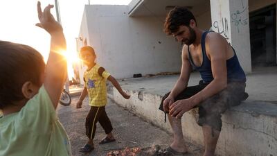 More than 100 Syrian refugees have made their homes in tents pitched inside an abandoned slaughterhouse. Here, a father barbecues food for his family.