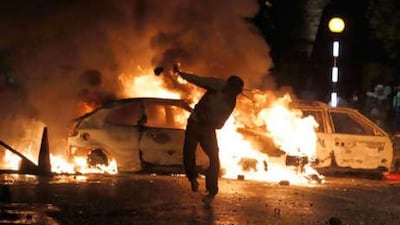 A Nationalist youth standing near burning vehicles throws a missile at police in the Ardoyne area of North Belfast.