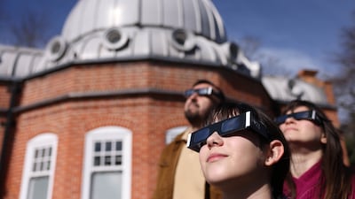 People wear protective glasses during a partial solar eclipse, at the Royal Observatory Greenwich in London. EPA
