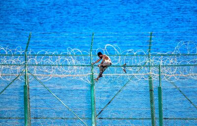 A migrant scales a fence into Cueta. AFP