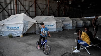A boy sits on a bicycle at the Skaramangas refugee camp, on the outskirts of Athens. AFP