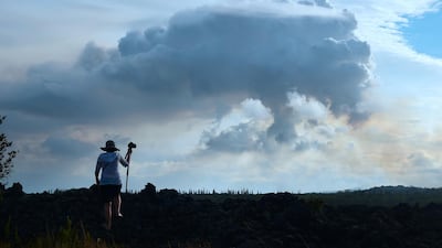 A man climbs onto a petrified lava flow from long ago for a picture of the plume of volcanic smoke in the distance over the area of Leilani Estates near the town of Pahoa. Frederic Brown / AFP