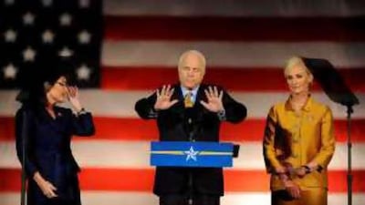 John McCain tries to quieten his supporters during his concession speech as his wife, Cindy, left, and Sarah Palin look on.