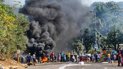 A crowd watches smoke billowing into the sky alongside a burning barricade in Durban. Mr Ramaphosa says there is no justification for violence and that it is damaging efforts to rebuild the economy.