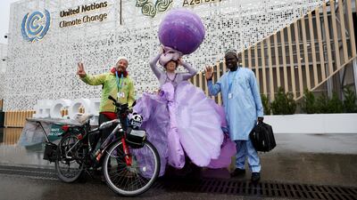 Chinese artist Kong Ning wears her Purple Shells installation at the Cop29 summit, alongside French climate activist David Ligouy, left. Reuters