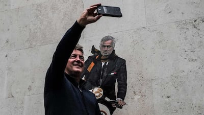 A man takes selfie in front of a mural depicting the new coach of AS Roma, Jose Mourinho, riding a motor scooter, on a wall of a building in the Testaccio district of Rome. AFP