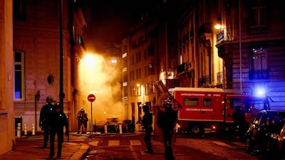 French riot police officers stand next to firefighters putting out a fire near the Champs-Elysees. AFP