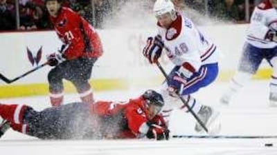 The Capitals' Michael Nylander, sliding on ice, and the Montreal Canadiens left wing Andrei Kostitsyn compete for a loose puck.