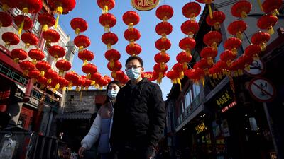People walk under traditional Chinese lanterns along an alley in Beijing. The biggest annual holiday, Lunar New Year, will usher in the Year of the Ox on Friday. AFP