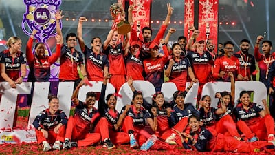 Royal Challengers Bengaluru players celebrate with the Women's Premier League trophy after defeating Delhi Capitals in the final at the Kotambi Stadium in Vadodara. AFP