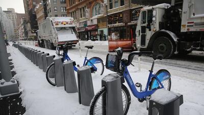 Garbage trucks plow past a Citi Bike station after winter storm Hercules in New York, United States. John Moore/Getty Images/AFP