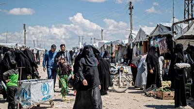 Women displaced from Syria's north-eastern Deir Ezzor province walk in a market inside Al Hol camp. AFP