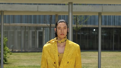 A loose, boxy suit in mustard yellow is covered in lemon-toned flowers on the runway at the Etro spring/summer 2023 menswear show.