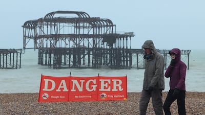 A couple walk past a public information sign on the beach ahead of the arrival of the storm, in Brighton. Reuters