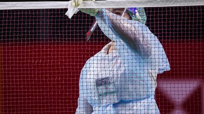 An official wearing a face mask and shield while cleaning the net, ahead of the Thailand Open badminton tournament in Bangkok. AFP