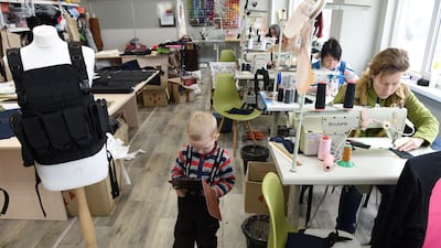 A 3-year-old boy watches cartoons on a tablet while his mother sews military vests for the Ukrainian army in the western city of Lviv. AFP