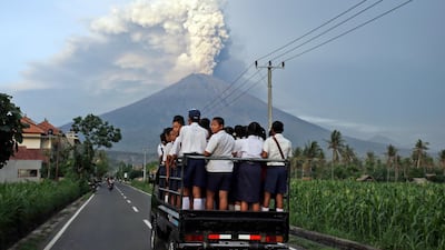Students in Bali head to school on a lorry with Mount Agung volcano spewing smoke and ash in the distance. Firdia Lisnawati / AP Photo