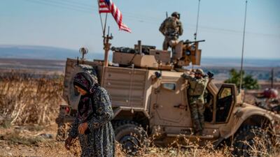 A Syrian elderly woman walks past a US armoured vehicle on a patrol in the village of Ein Diwar in Syria's northeastern Hasakeh province. AFP