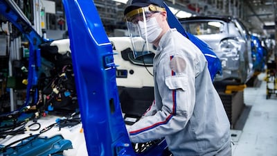 An employee demonstrates precautionary measures on the assembly line at the PSA Peugeot Citroen plant in Trnava, Slovakia. AFP