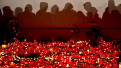 People cast shadows on a wall as they wait to light candles and lay flowers outside the compound that housed the nightclub where a fire occurred in the early morning hours in Bucharest, Romania. Vadim Ghirda / AP Photo