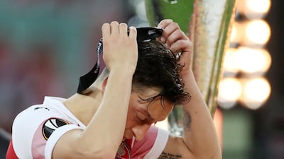 Arsenal's Mesut Ozil removes his medal as he walks past the trophy after the match. REUTERS.