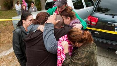Jeremy Bush, center with hand on head, is embraced by family and friends outside his home on Friday after his brother fell down a sinkhole under their house. AP Photo