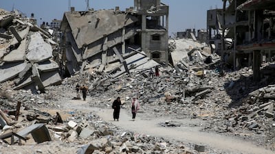 Palestinians walk past the rubble of houses destroyed during the Israeli military offensive in Khan Younis. Reuters