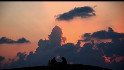 Cloud busters: a Palestinian family sit on a hill and watch the sun set in Rafah, southern Gaza Strip. Mohammed Saber / EPA