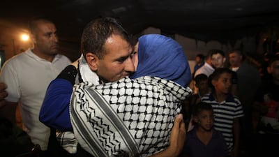 A released Palestinian prisoner Hosni Sawalha, left, is hugged upon his arrival to his family house in in Azmout village near Nablus in the West Bank. AP Photo / Nasser Ishtayeh