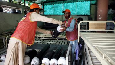 Aziz Ullah, 60, and 21-year-old Muhammad Usman, both aid workers of Alamgir Welfare Trust, arrange oxygen cylinders at the warehouse of the non-profit organisation in Islamabad. Imran Mukhtar/ The National