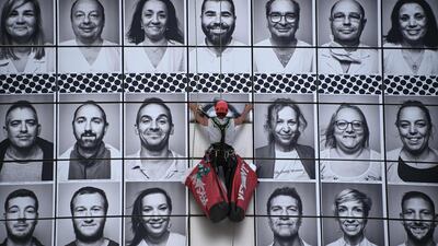 A worker pastes portraits of healthcare workers on the facade of the Opera Bastille, Paris. AFP