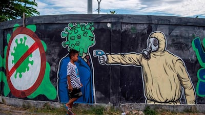 A boy walks past a mural depicting the Covid-19 coronavirus in Surabaya, East Java. AFP