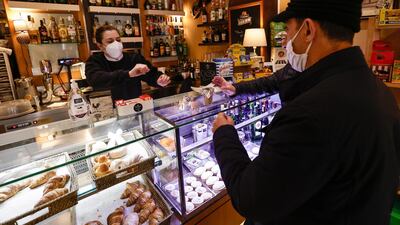 A worker serves a customer at a coffee shop in Naples, Italy, as the town is downgraded from a red to an orange zone. Reuters