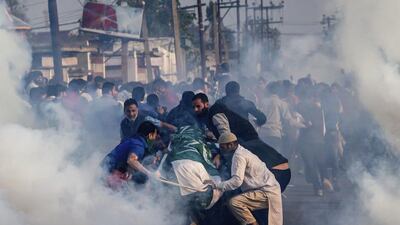 Relatives and neighbours huddle around the body of 12-year-old Junaid Ahmed as tear gas shells fired by Indian policemen explode near them during his funeral procession in Srinagar, Indian controlled Kashmir, Saturday, Oct. 8, 2016. (AP Photo/Dar Yasin)
