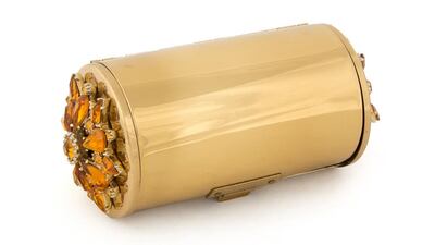 A gold metal minaudière with a citrine crystal floret embellishment features three compartments, including one for loose powder with a cotton buffer, mirror and comb. Courtesy Julien’s Auctions