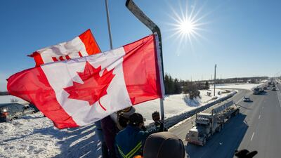 Supporters wave flags in Ontario, Canada, on January 29, as a trucker convoy makes its way to Parliament Hill in Ottawa to protest against new Covid-19 measures and vaccine mandates. AP