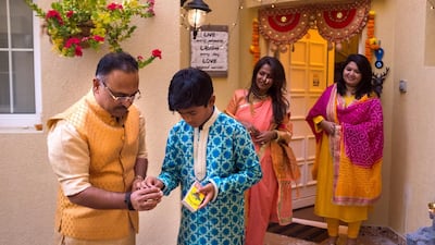 Sandeep Khursude and his son, Adi, light candles outside their home for Diwali. Reem Mohammed/The National
