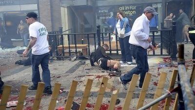 Injured people lie with debris on the pavement near the Boston Marathon finish line following an explosion.