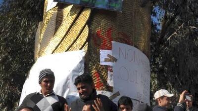 FILE - In this Jan. 19, 2011 file photo youth's gather below the portrait of Mohamed Bouazizi in Sidi Bouzid, central Tunisia.