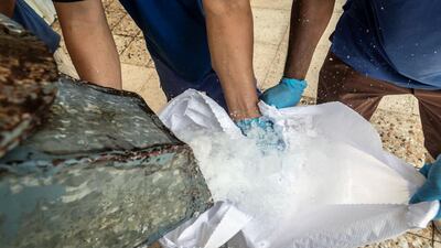 An ice crusher breaks up a 25-kilogram ice block into ice chips destined for use at a seafood company. About 12,000 small blocks are produced daily at the Dubai Investment Park factory and shipped across the UAE in a fleet of 75 lorries. Antonie Robertson / The National