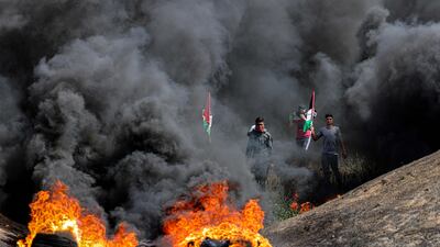 Palestinian flags shrouded in smoke from burning tyres during a demonstration near the border with Israel, east of Gaza City. AFP