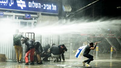 Israeli protesters run as police officers use water canon after clashes erupted during a demonstration against the government's judicial overhaul. Getty