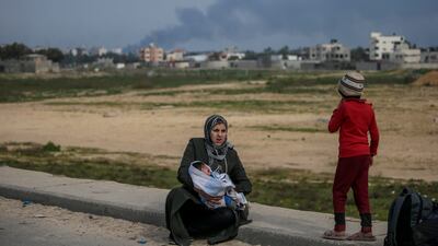 A Palestinian mother takes a rest after crossing from the northern Gaza Strip to the south along Al Rashid road this week. EPA