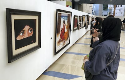 A visitor to the UAE Women in Art exhibition takes a photo at Zayed University in Dubai. Satish Kumar for The National